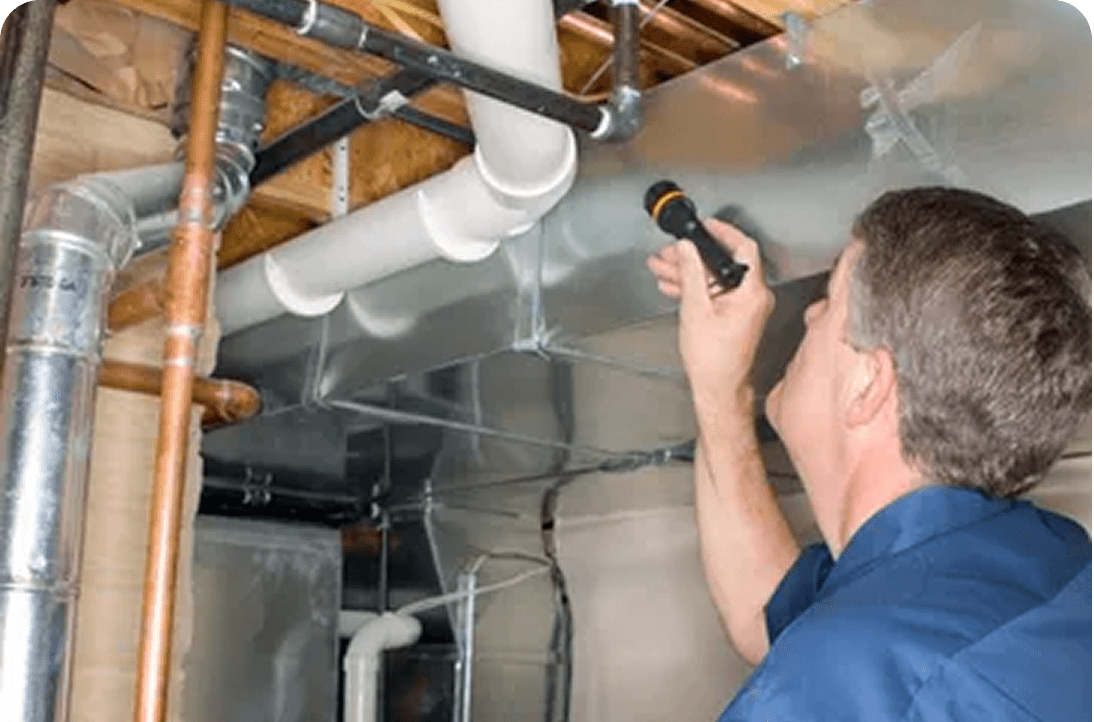 Inspector examining pipes with flashlight in basement.