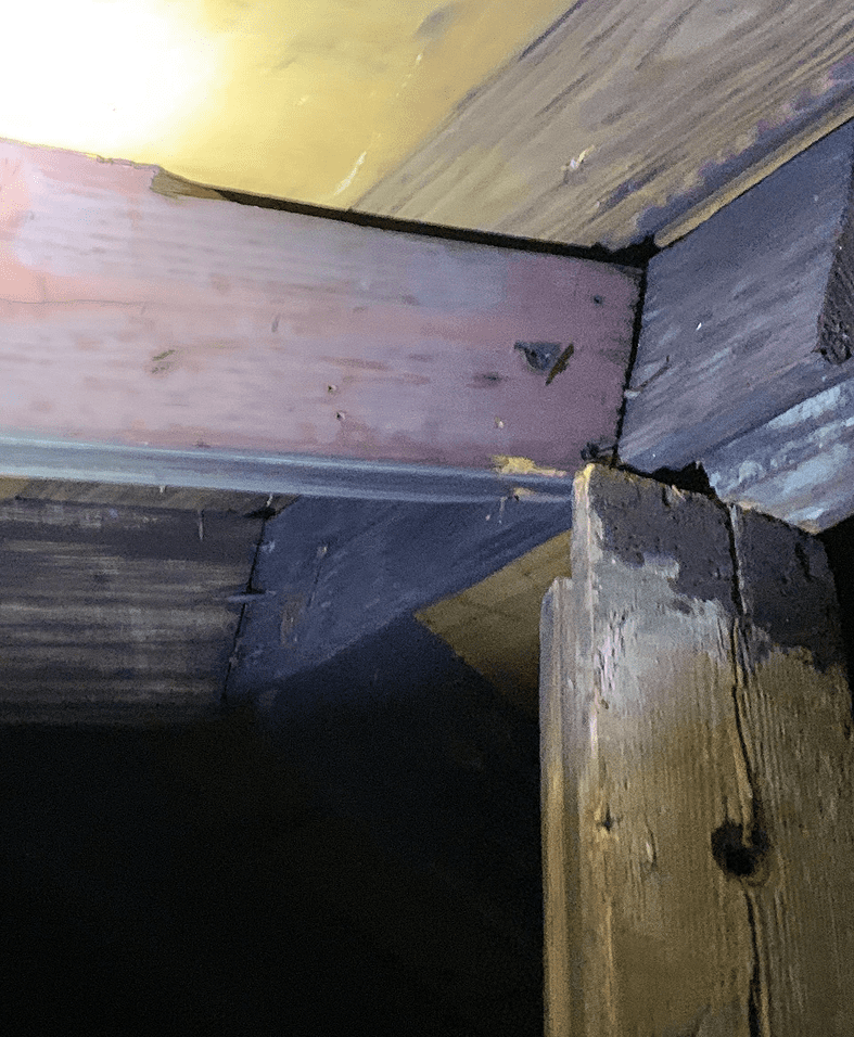 Wooden beams in dimly lit attic.