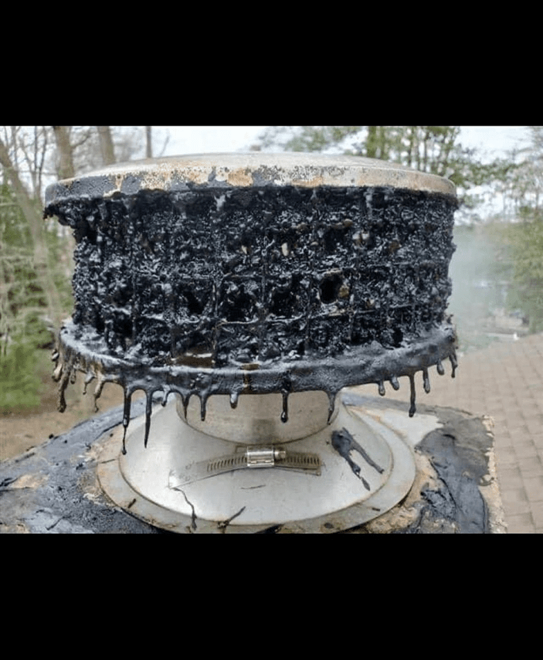 Chimney cap covered in black creosote buildup.
