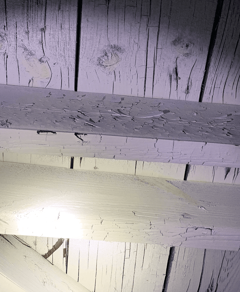 Peeling paint on wooden beams with light.