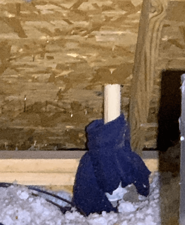Pipe insulated with cloth in attic space.