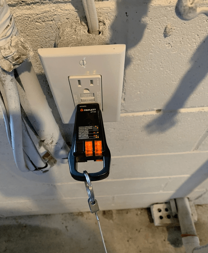 Electrical outlet with a plugged-in circuit tester.