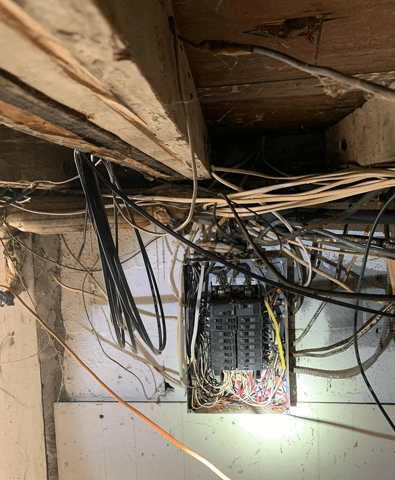 Tangled wires in an electrical panel box.