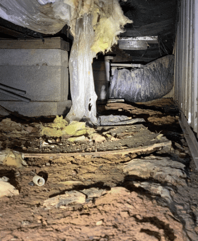 Crawl space with insulation and debris.
