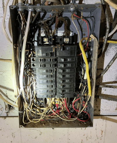 Electrical panel with numerous exposed wires.