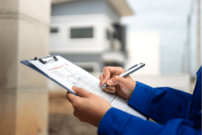 Person writing on clipboard outside a building.