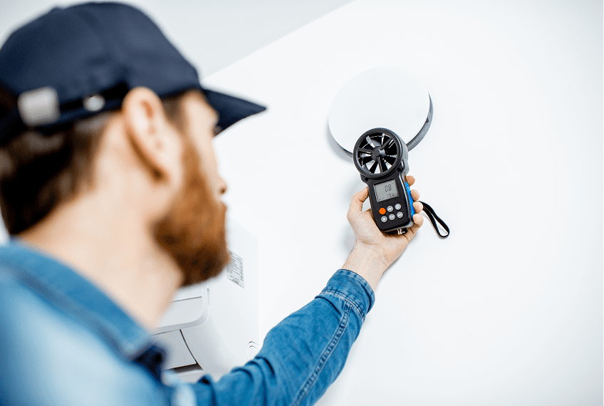 Technician measuring air flow with device.